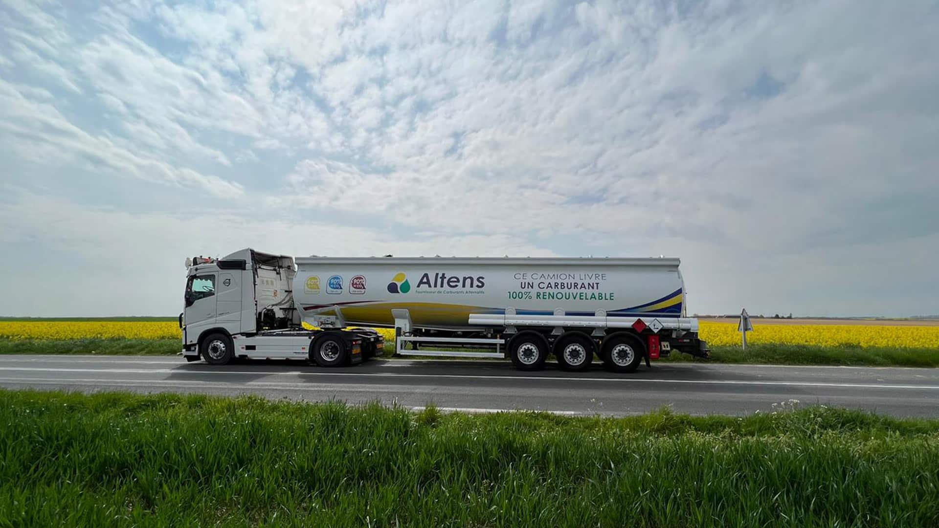 camion aux couleurs d'Altens roulant devant un champ de colza